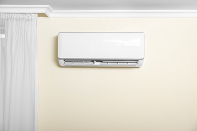 Modern air conditioner on white wall indoors