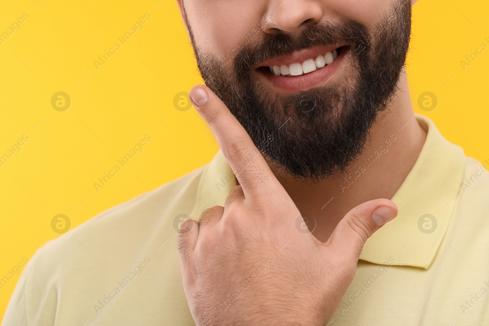 Photo of Man showing his clean teeth and smiling on yellow background, closeup