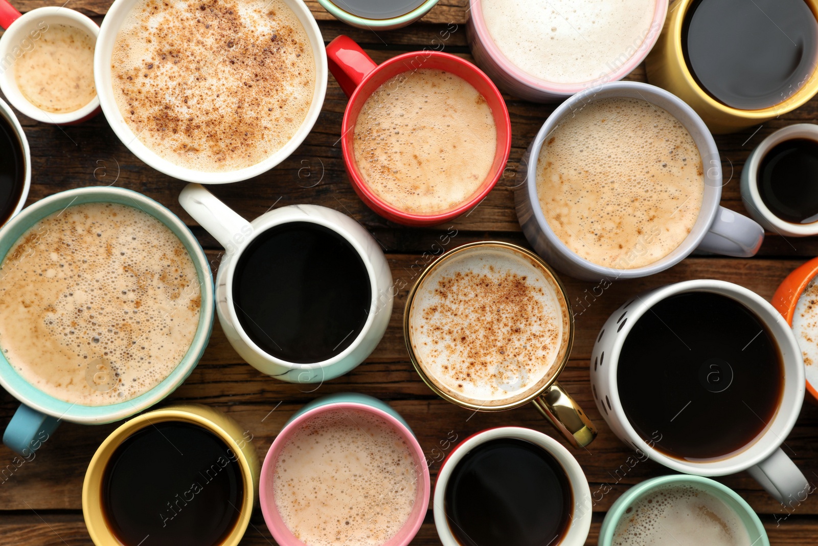 Photo of Many cups of different coffees on wooden table, flat lay