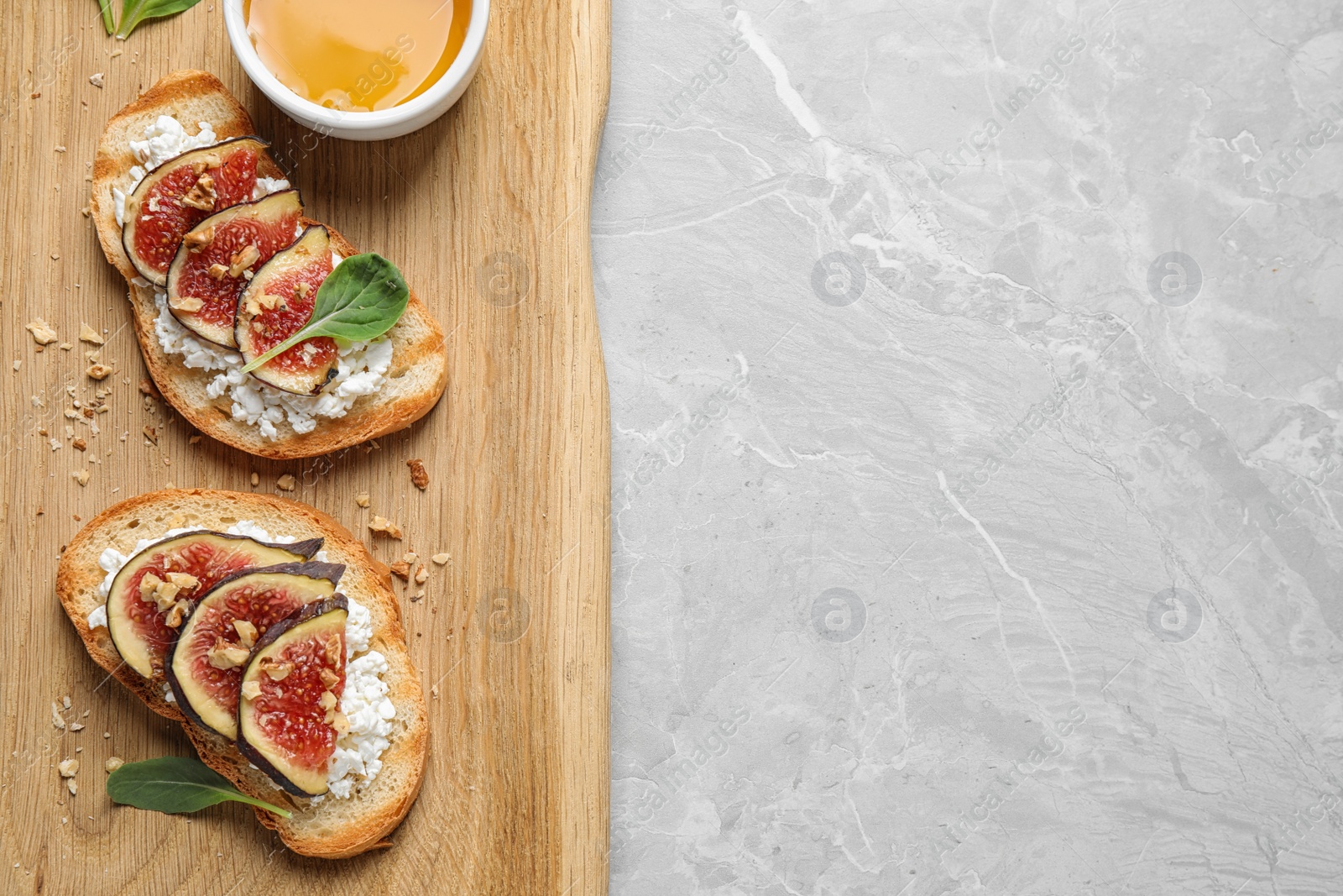 Photo of Bruschettas with cheese, figs and honey served on marble table, top view. Space for text