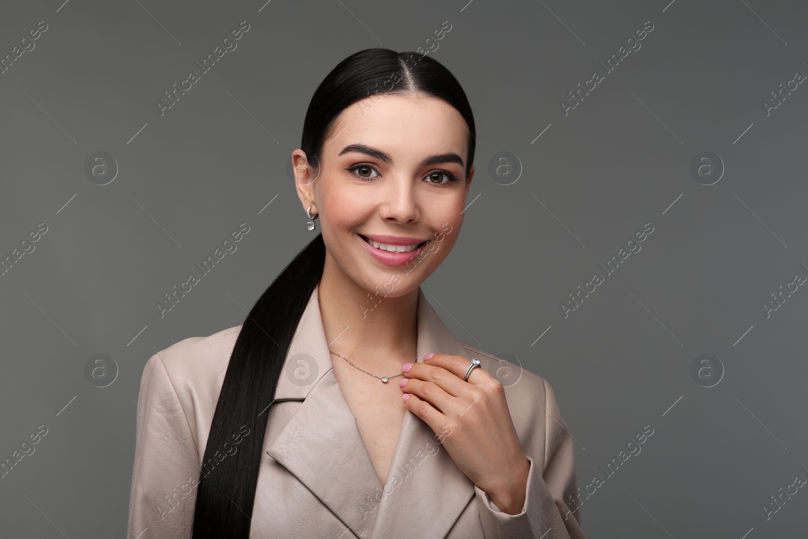 Photo of Beautiful young woman with elegant jewelry on dark grey background