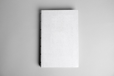 Hardcover book on light grey background, top view. Space for design