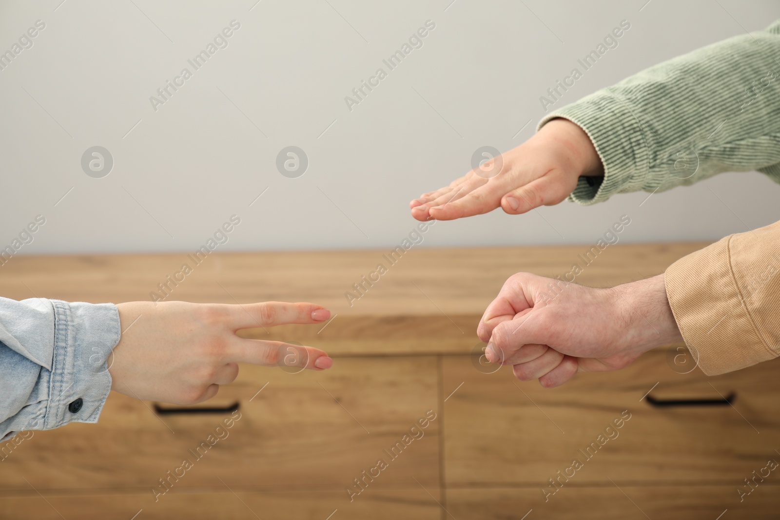 Photo of People playing rock, paper and scissors indoors, closeup