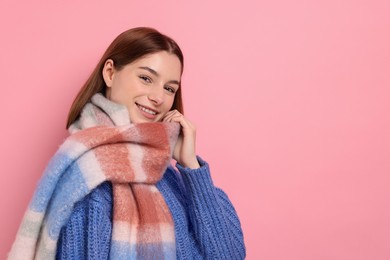 Beautiful woman in warm scarf on pink background, space for text