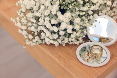 Photo of Pocket mirror, engagement rings and beautiful bouquet on wooden table. Wedding day
