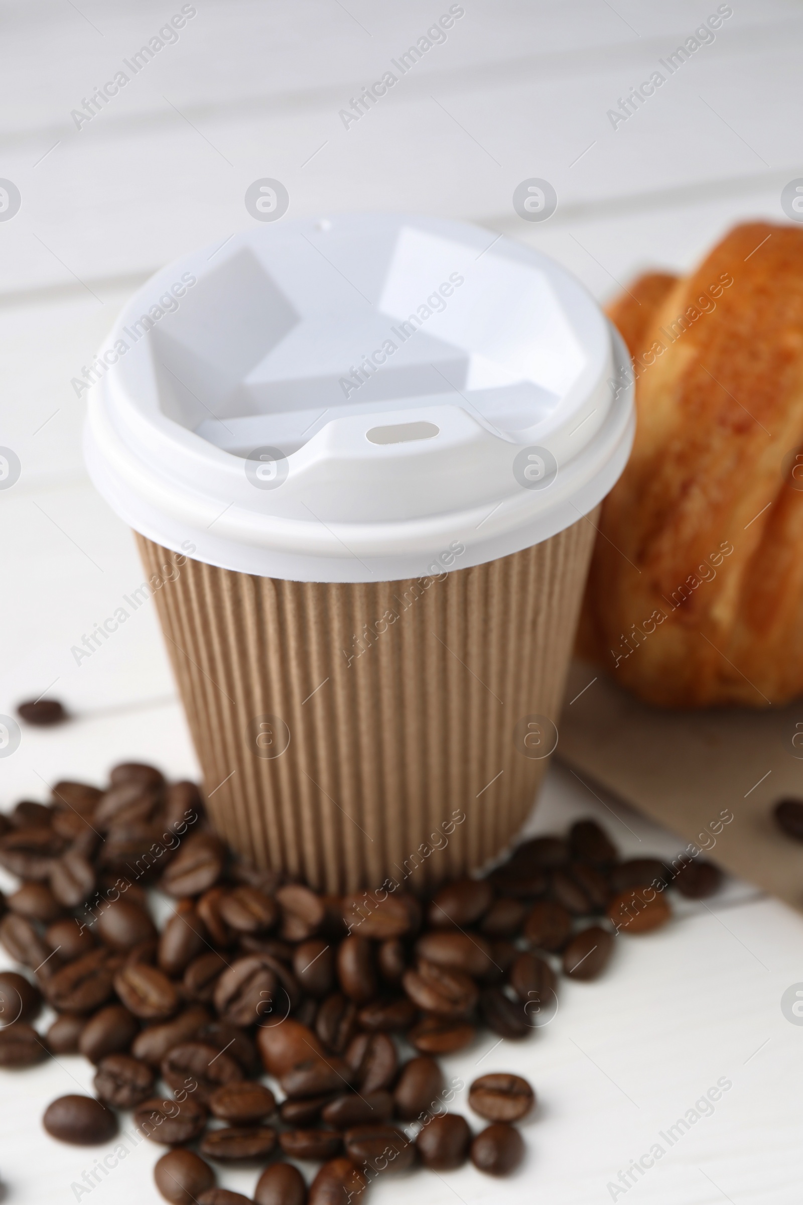 Photo of Coffee to go. Paper cup with tasty drink and beans on white table