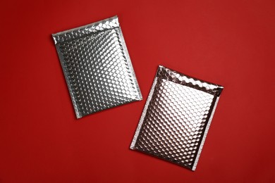 Two padded envelopes with bubble wrap on red background, flat lay