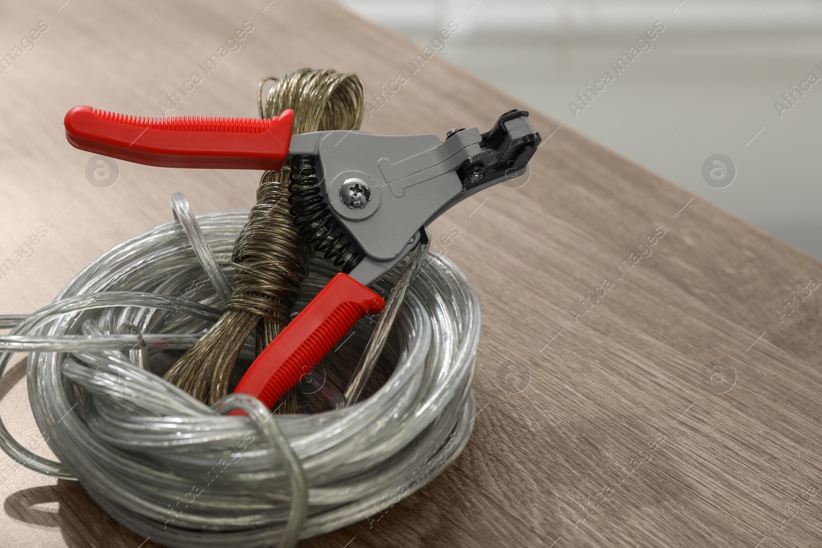 Photo of Cutters and stripped wire on wooden table, closeup. Space for text