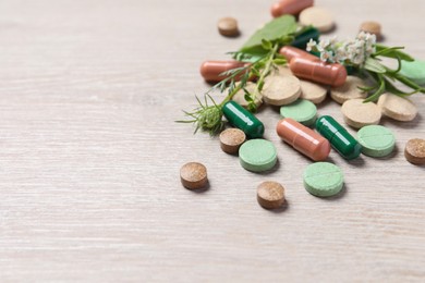 Different pills and herbs on wooden table, closeup with space for text. Dietary supplements