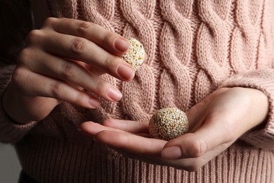 Photo of Woman holding delicious vegan candy balls with sesame seeds, closeup