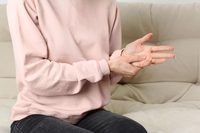 Photo of Woman suffering from trigger finger on sofa, closeup