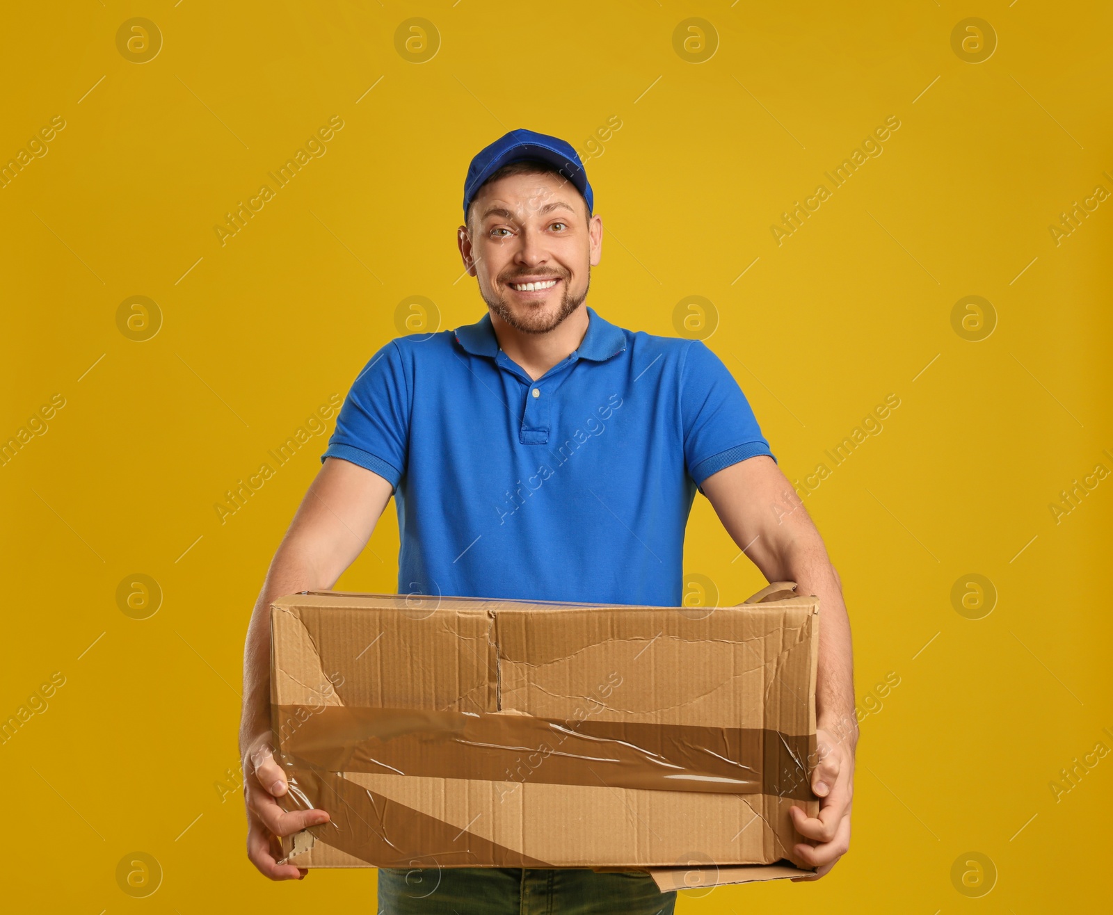 Photo of Courier with damaged cardboard box on yellow background. Poor quality delivery service