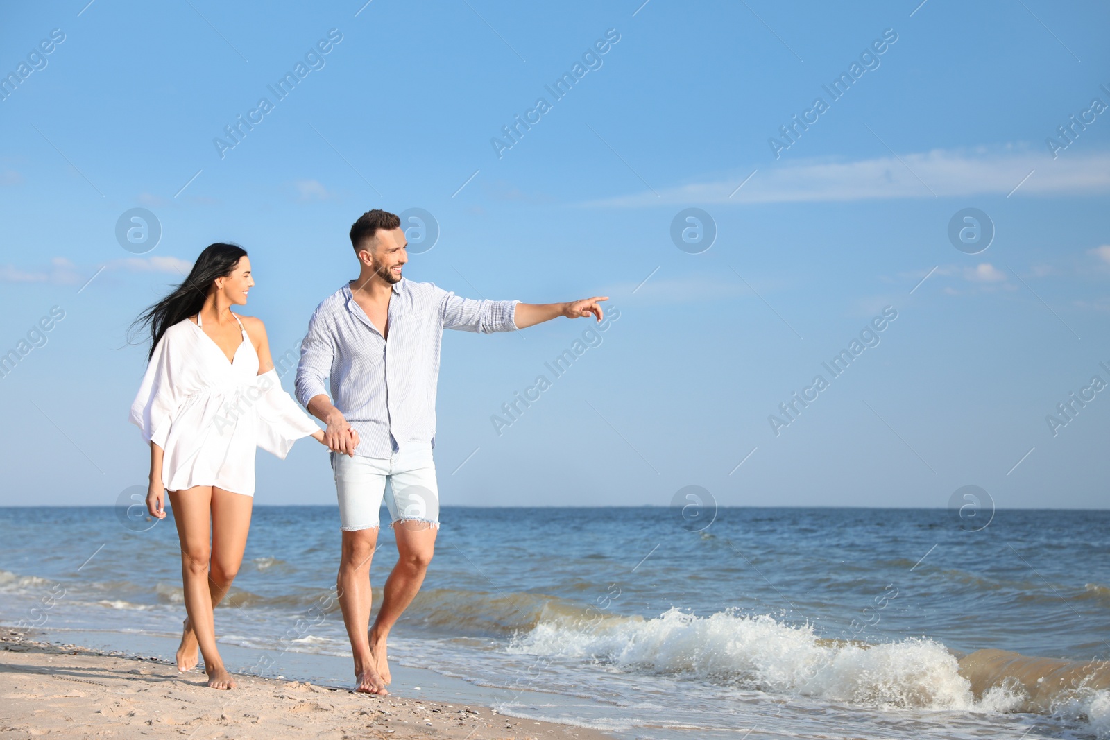 Photo of Happy young couple walking at beach on sunny day