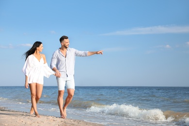 Photo of Happy young couple walking at beach on sunny day