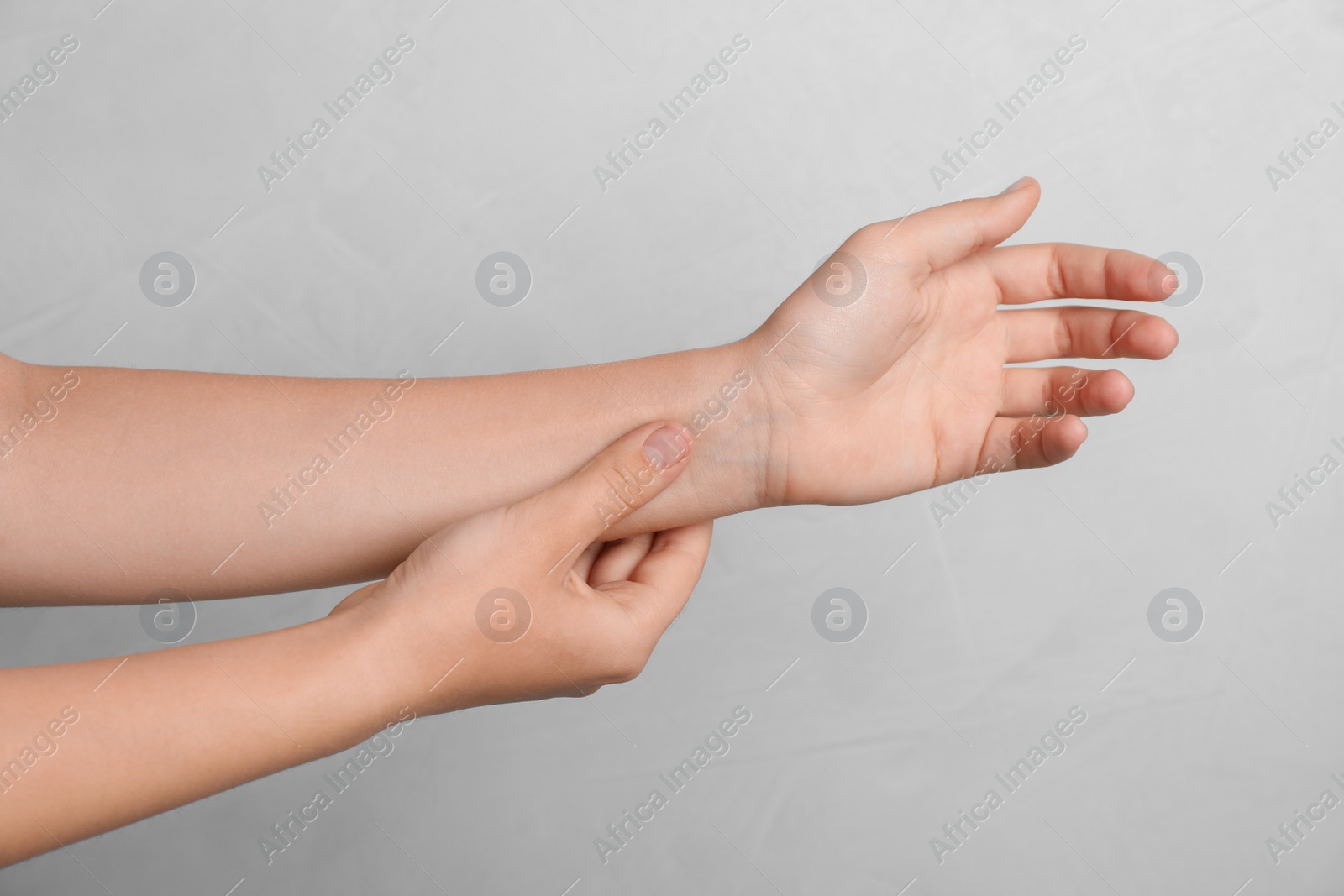 Photo of Woman checking pulse on gray background, closeup