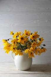 Photo of Beautiful yellow flowers on light wooden table