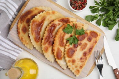 Photo of Delicious fried chebureki and parsley served on white table, flat lay