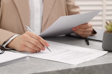 Photo of Woman signing document at table, closeup view