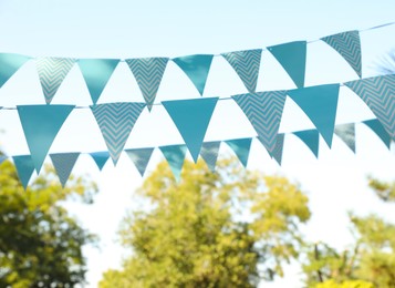 Photo of Light blue bunting flags in park. Party decor