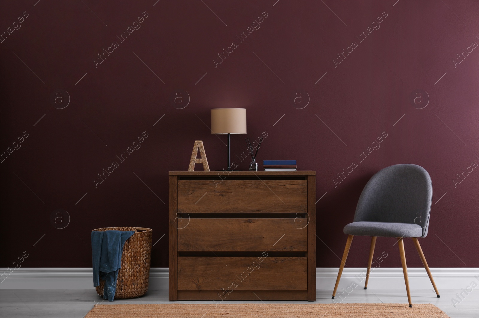 Photo of Elegant room interior with stylish chest of drawers, wicker basket and comfortable chair