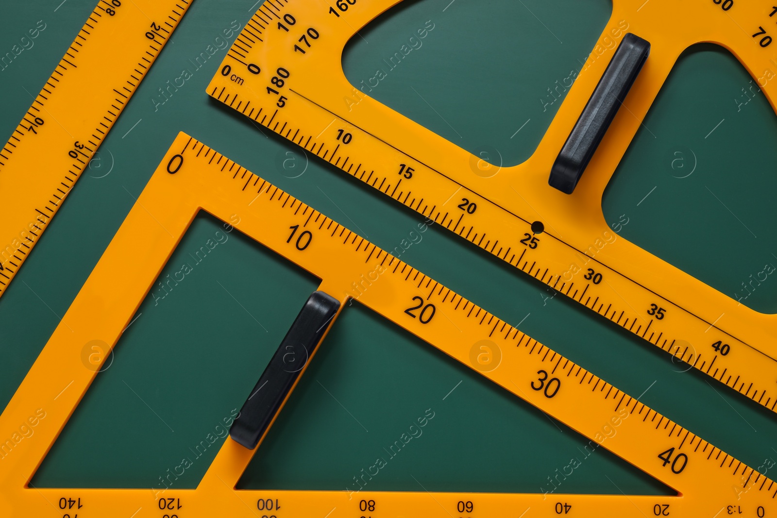 Photo of Protractor, triangle and ruler on green chalkboard, flat lay