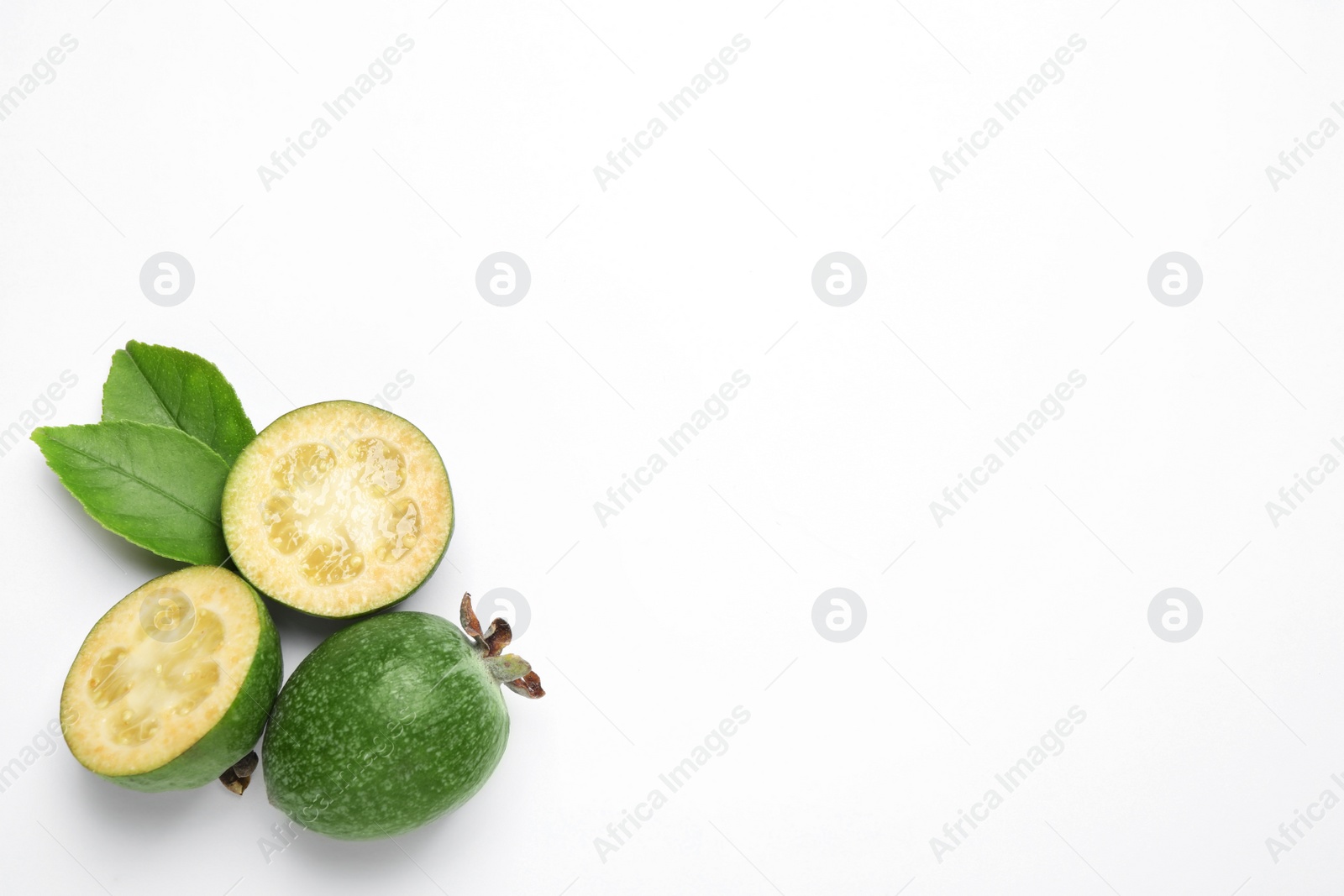 Photo of Cut and whole feijoas with leaves on white background, top view