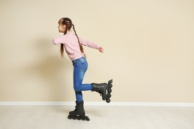 Photo of Cute girl with inline roller skates near color wall