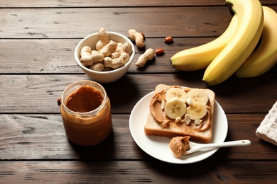 Toast bread with peanut butter and banana slices on wooden table