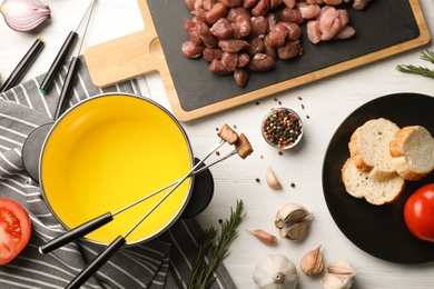 Flat lay composition with oil pot and meat fondue ingredients on wooden background