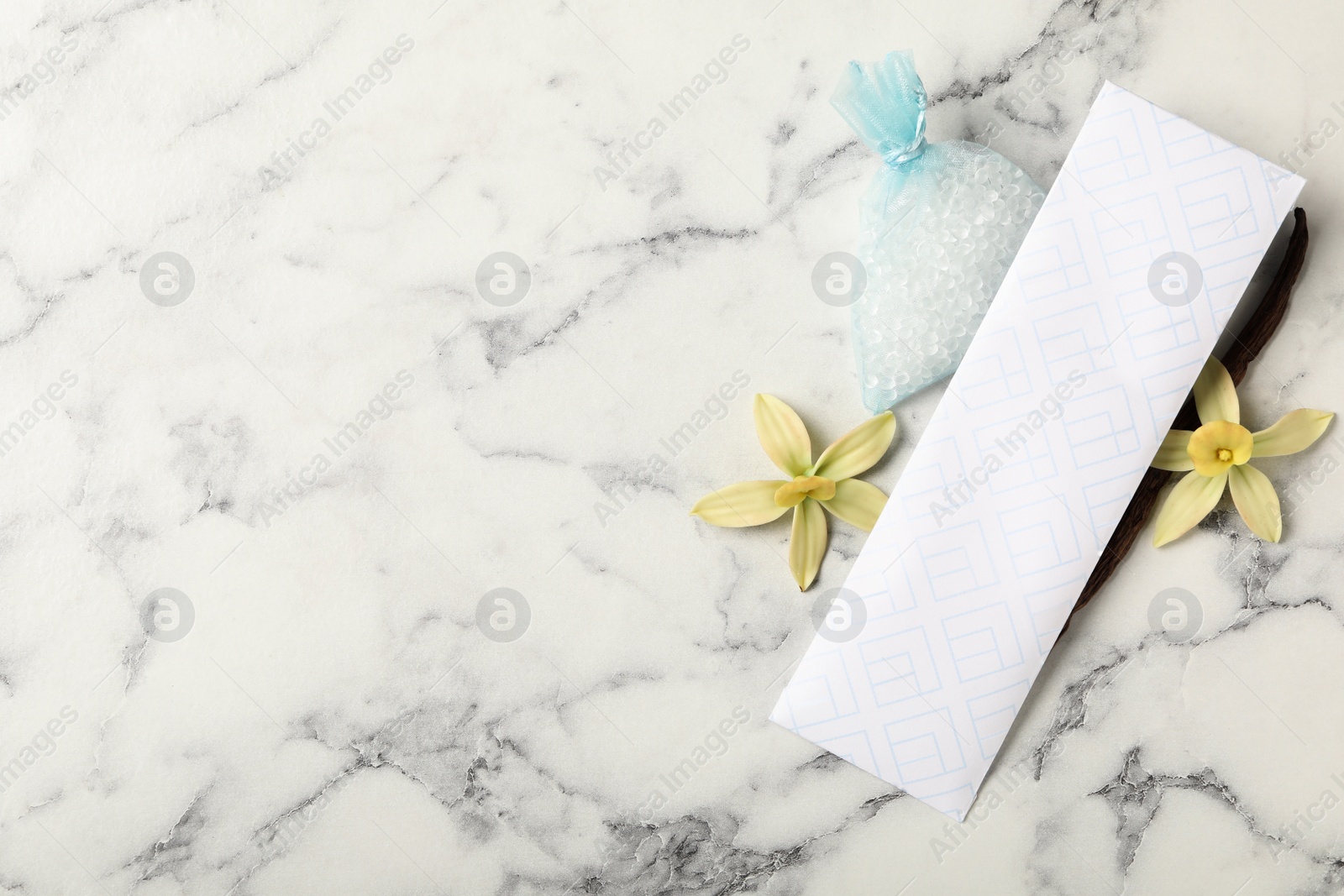 Photo of Scented sachets, vanilla and flowers on white marble table, flat lay. Space for text