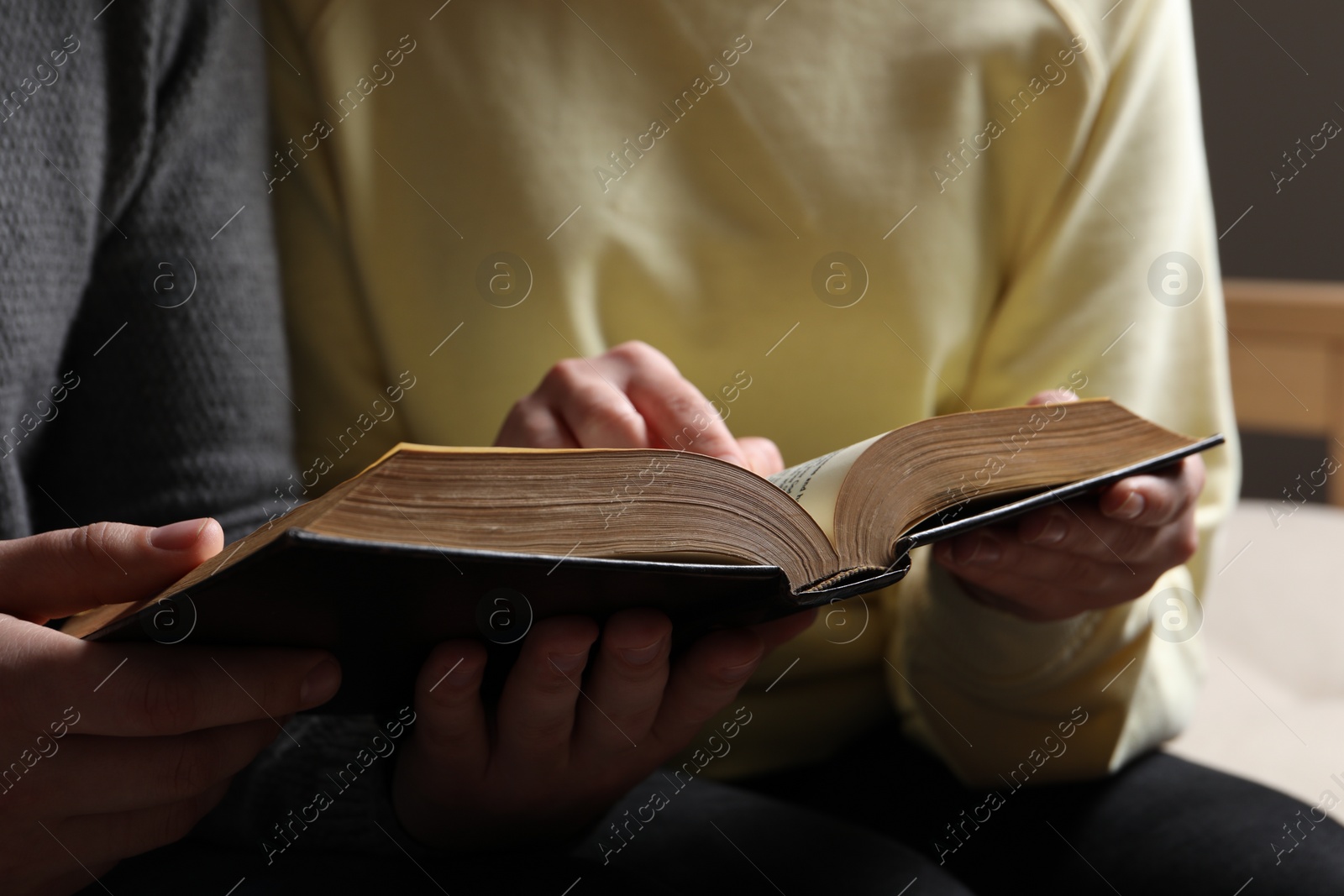 Photo of Couple sitting and reading holy Bible indoors, closeup