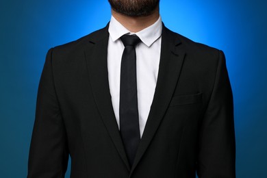Businessman in suit and necktie on blue background, closeup