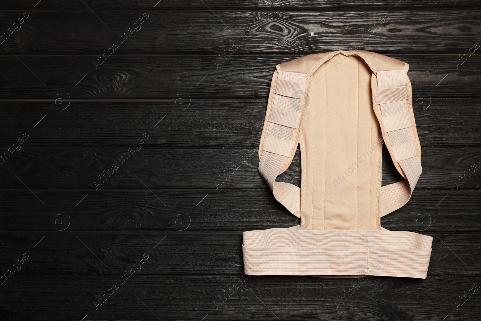 Photo of Beige posture corrector on black wooden table, top view. Space for text