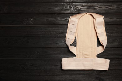 Photo of Beige posture corrector on black wooden table, top view. Space for text