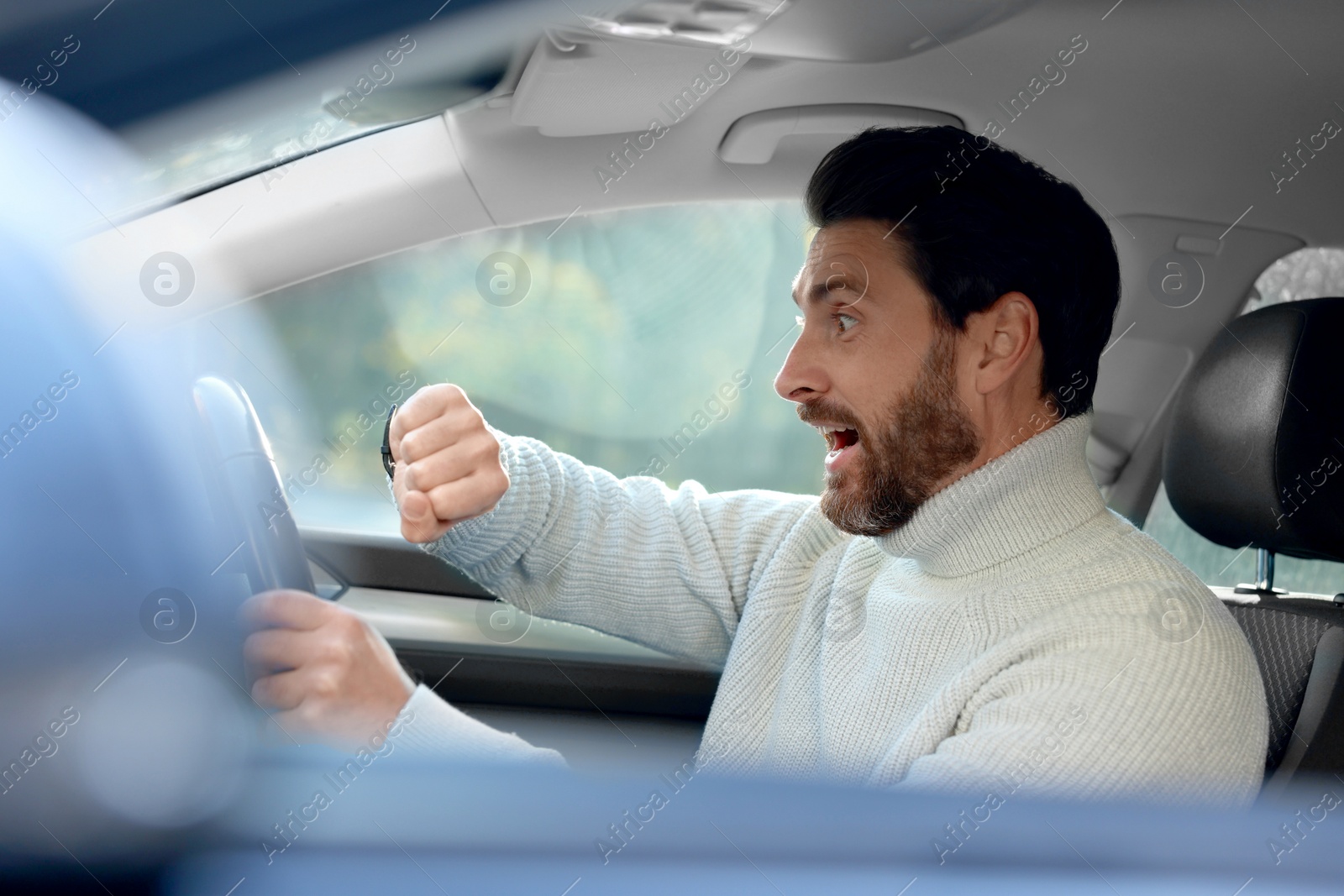 Photo of Emotional man checking time on watch in car. Being late concept