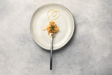 Photo of Heart made with spaghetti and fork on grey table, top view