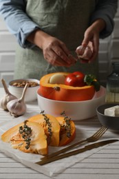 Fresh ripe pumpkin slices with aromatic thyme on tablecloth, selective focus. Space for text