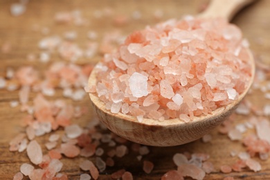 Photo of Spoon and pink himalayan salt on table, closeup