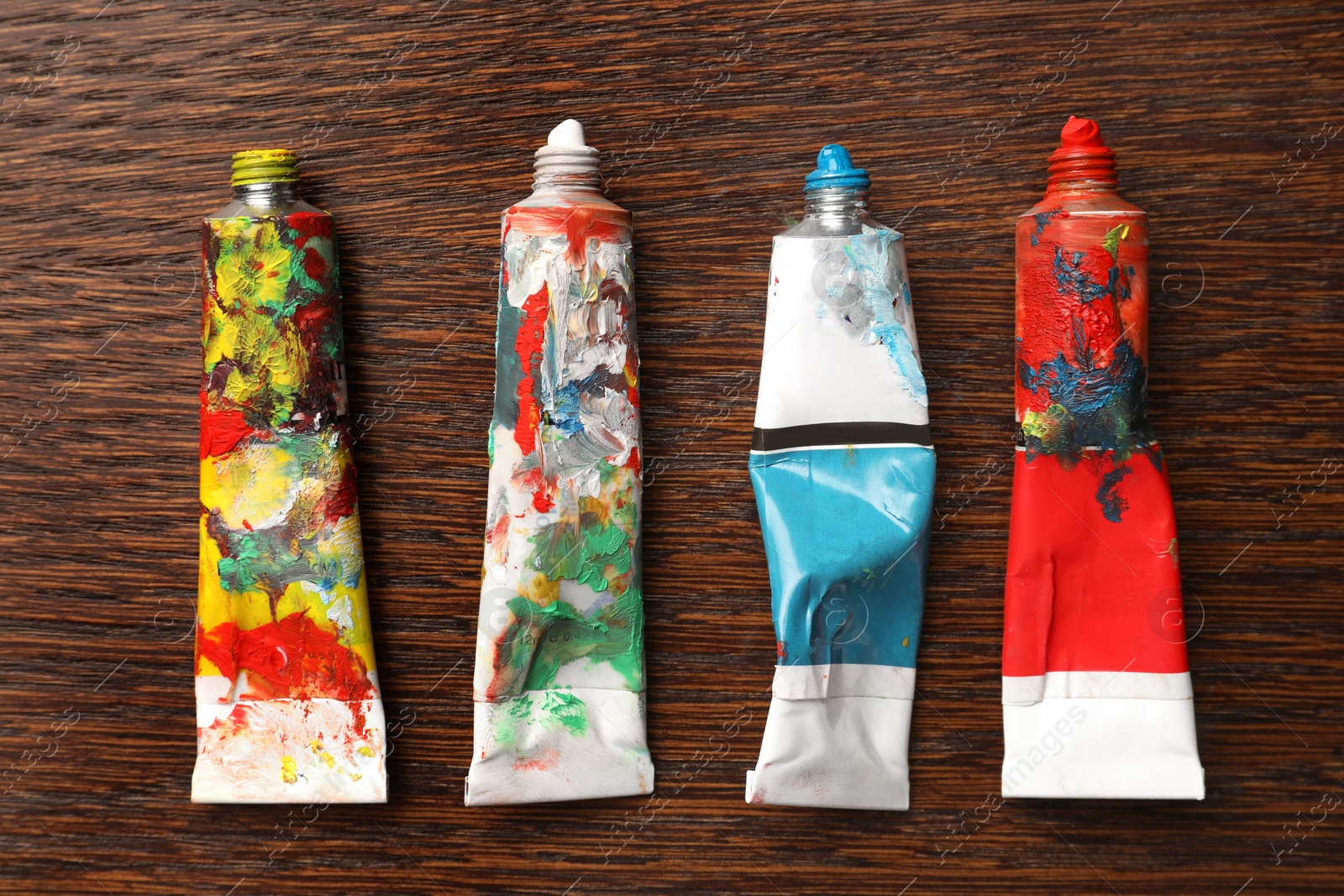 Photo of Tubes with oil paints on wooden table, flat lay