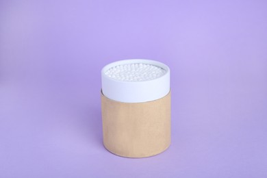 Photo of Container with new cotton buds on violet background