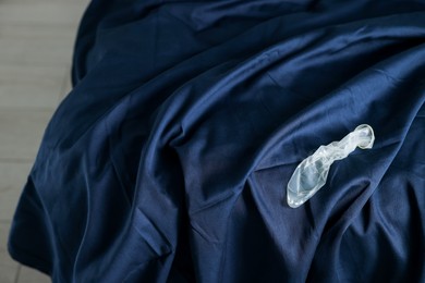 Photo of Unrolled condom on bed, above view. Safe sex