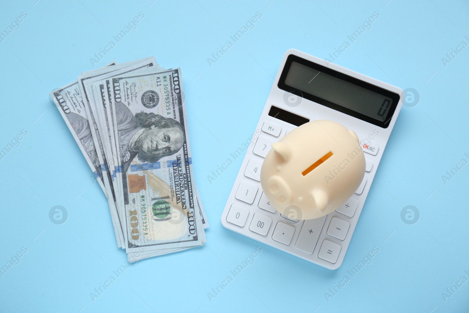 Photo of Piggy bank, banknotes and calculator on light blue background, flat lay