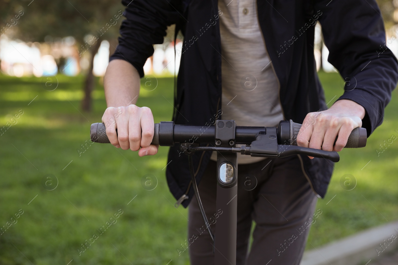 Photo of Man riding modern electric scooter in park, closeup