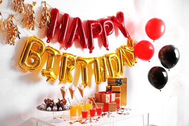 Photo of Treats and gifts on table in room decorated for birthday party with different balloons