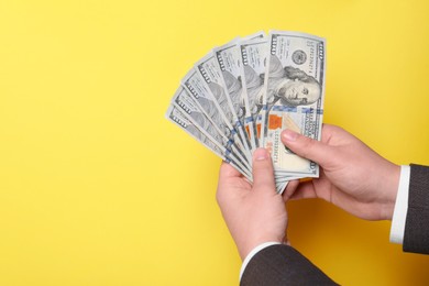 Photo of Man holding money on yellow background, closeup. Space for text. Currency exchange