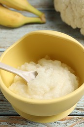 Baby food. Bowl with cauliflower puree and ingredients on rustic wooden table, closeup