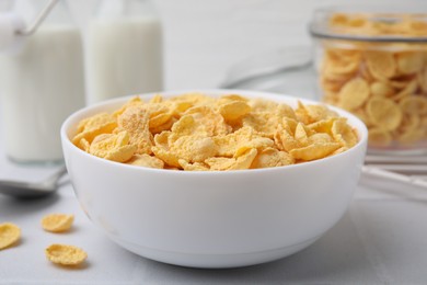 Photo of Tasty crispy corn flakes in bowl on white table, closeup. Breakfast cereal