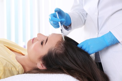 Photo of Young woman with hair loss problem receiving injection in salon