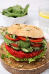 Photo of Tasty vegan burger with vegetables, patty and microgreens on white table, closeup