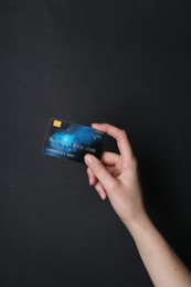 Photo of Woman holding credit card on black background, closeup